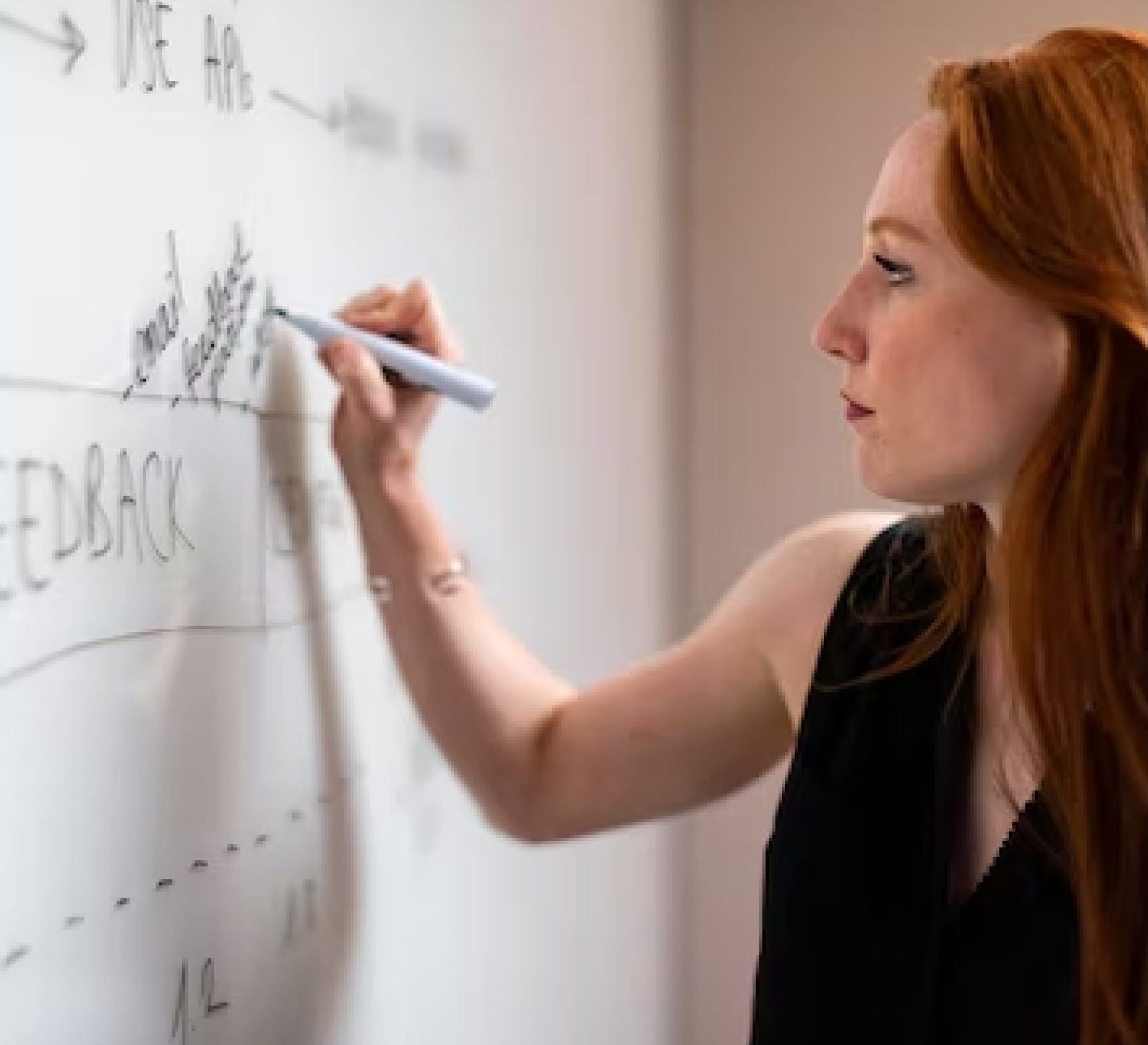 Junge Wissenschaftlerin macht sich Notizen auf einem Whiteboard