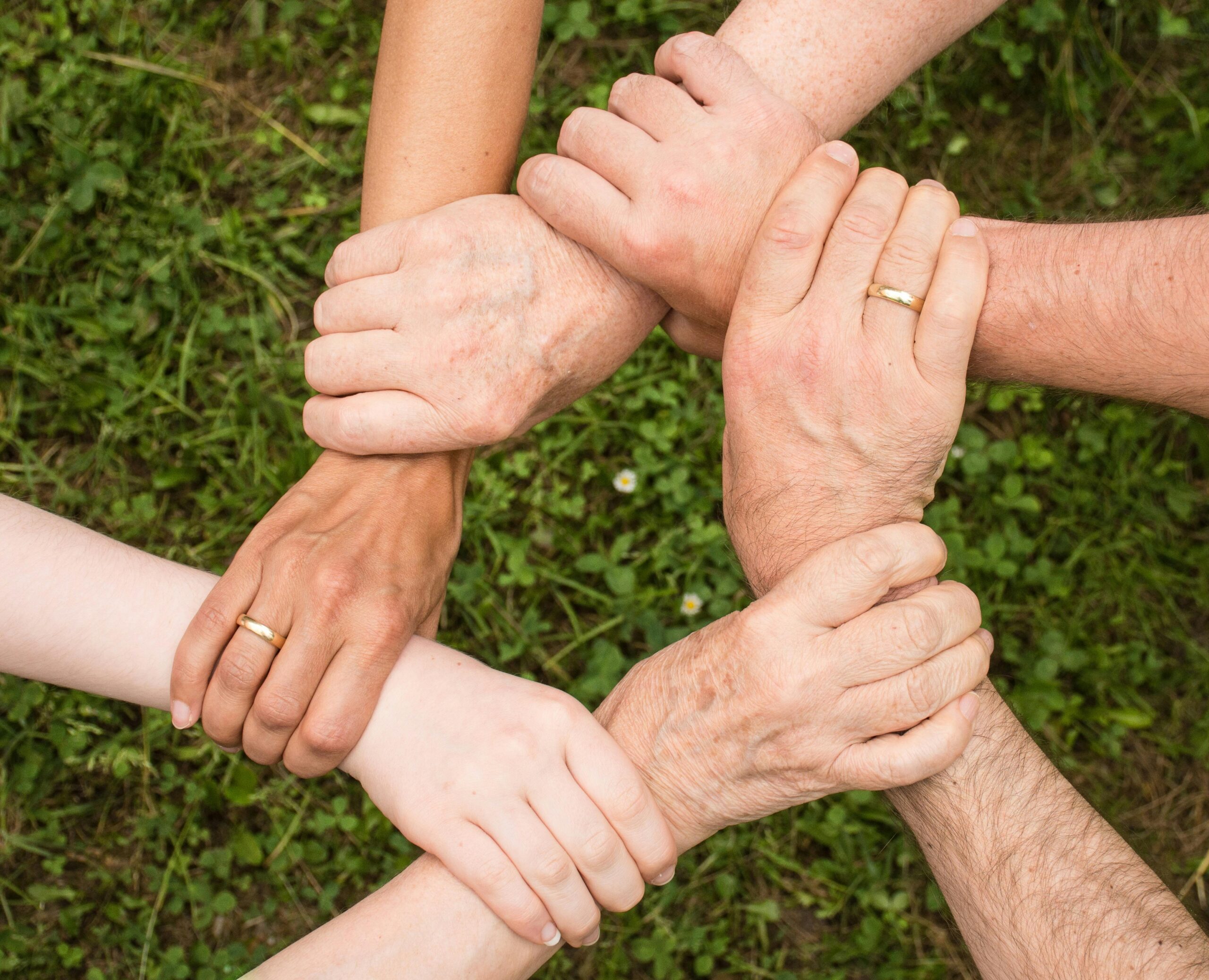 People hold each other by the wrists. The detail shows only her hands, which form a circle.